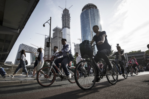 Cyclists ride along a road near the China Central Television headquarters in Beijing. There is a lot of interest in converting shopping complexes and similar realty into office spaces in Beijing this year. (Photo provided to China Daily)