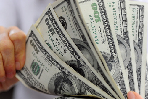 A teller counts and arranges dollar notes at an Agricultural Bank of China branch in Qionghai, South China's Hainan Province. (Photo/China Daily)
