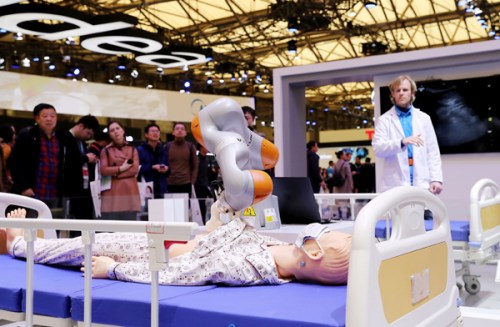 Visitors watch a medical robot designed by KUKA at the Appliance and Electronics World Expo in Shanghai on Thursday. (Photo/Xinhua)