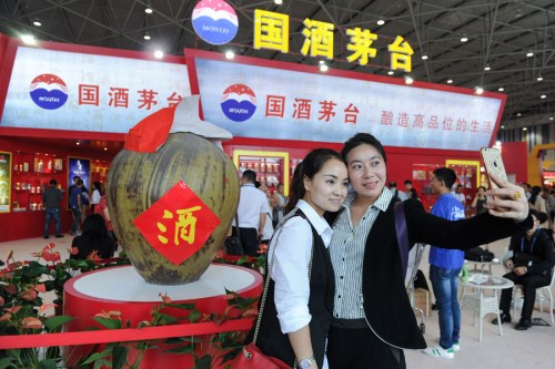 Two visitors take a selfie in front of a huge wine jar at the Kweichow Moutai exhibition stand, at the 2016 China (Guizhou) International Wine Exposition, held in Guiyang, Guizhou Province. (Photo/China News Service)