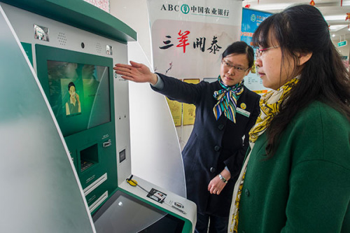 An employee of Agricultural Bank of China Ltd helps a client at an outlet of the bank in Zhenjiang, Jiangsu Province. (Photo by Feng Jiangjiang/for China Daily)