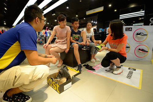 A customer tries on an Adidas shoe at the company's store in Datong, Shanxi Province. (Photo by Hu Yuanjia/for China Daily)