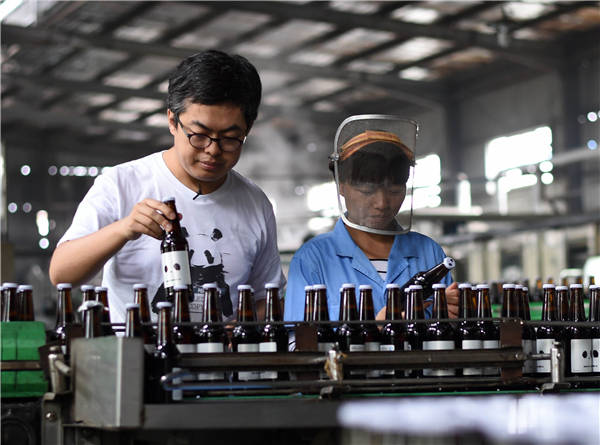 Craft-beer breweries are enjoying growing demand for their products. Pan Dinghao (left) casts a critical eye over his brewery's output at the Panda Brew in Yiyang, Hunan province. He founded the venture in 2013. (Li Ga / Xinhua)