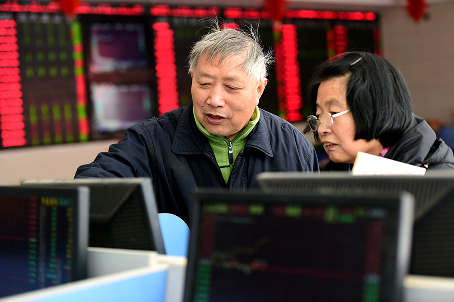 Investors check stock prices at a securities brokerage in Fuyang, East China's Anhui province. (Photo/China Daily)