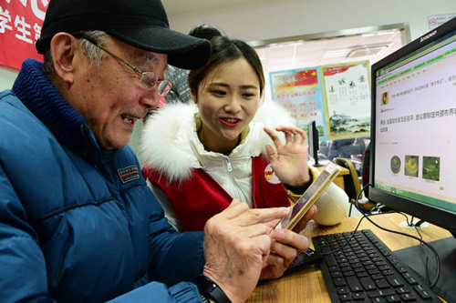 A volunteer helps a senior citizen surf the internet in Zhenjiang, Jiangsu Province. (Photo by Shi Yucheng/for China Daily)