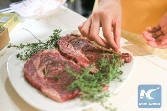 Photo taken on Nov. 2, 2017 shows a local resident marinating beef imported from the United States, in Shanghai, east China. (Xinhua/Meng Dingbo)