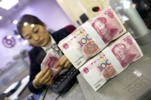 A cashier at a bank in Taiyuan, Shanxi province, counts renminbi notes. (Photo/China News Service)
