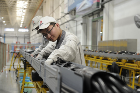 CRRC employees operate an assembly line of the company in Qingdao, Shandong province. (Photo by Zhang Jingang/For China Daily)