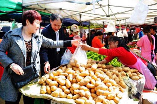 Consumers buy vegetables at a market in Qingdao, Shandong Province. (Photo by Yu Fangping/For China Daily)