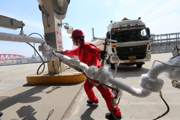 An employee shifts the LNG pipeline after filling the transport vehicle at the CNPC LNG center in Jiangsu province. (Photo for China Daily/Xu Congjun)