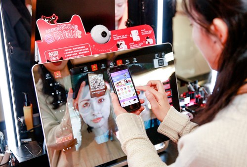 A customer uses a mobile app to select cosmetics for trial at a Tmall pop-up store in a shopping mall in Shanghai. (Photo provided to China Daily)