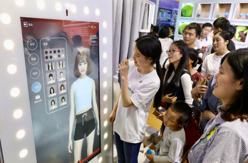 Visitors are amazed at an intelligent dressing mirror on show at the first Digital China Summit in Fuzhou, Fujian Province. (Photo by Zhu Xingxin/China Daily)