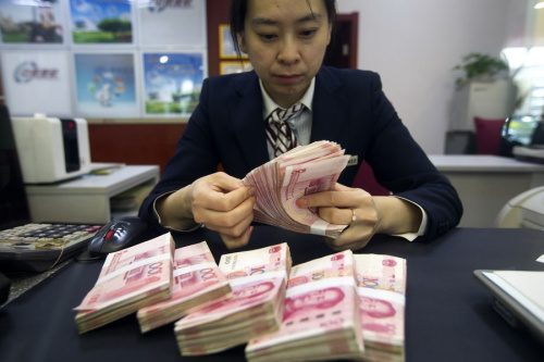 A clerk counts cash at a bank outlet in Taiyuan, Shanxi Province. (Photo by Zhang Yun/China News Service)
