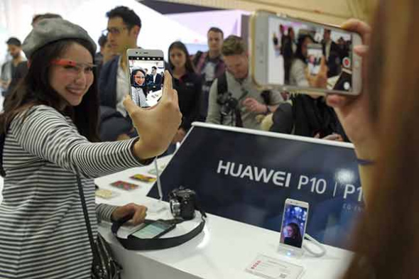 A visitor takes a selfie with a Huawei smartphone at a high-tech exhibition in Barcelona, Spain.(Photo provided to China Daily)