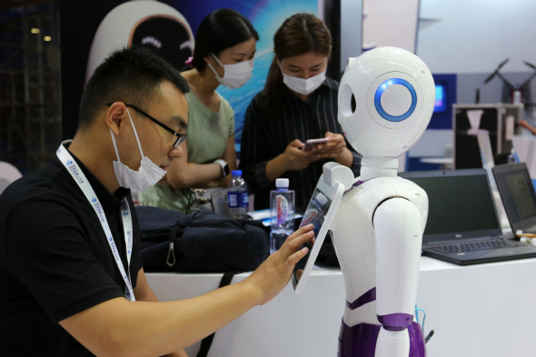 An exhibitor calibrates a robot before the opening of the World Robot Conference. (Photo: China Daily/Wang Zhuangfei)