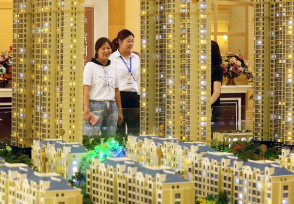A saleswoman (center) talks with customers at a real estate sales office in Huai'an, East China's Jiangsu province. (Photo by Zhou Changguo/China News Service)