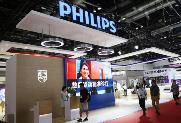 Visitors pass through the stand of Royal Philips NV at the 26th CHINA-HOSPEQ medical equipment exhibition held in Beijing. (Photo/China Daily)