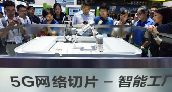 Visitors observe a 5G-supported robot at a high-tech exhibition in Shanghai. (Photo by Long Wei/For China Daily)
