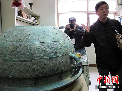 Researcher Zhang Guangmin introduces the restoration project for the ancient bathtub.