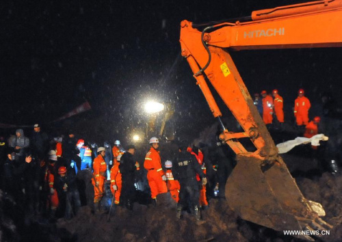 Rescuers and an excavator work at the mud-inundated debris after a landslide hit Gaopo Village in Zhenxiong County, southwest China's Yunnan Province, Jan. 11, 2013. The death toll from a landslide that hit Gaopo Village on Friday has risen to 42, after m