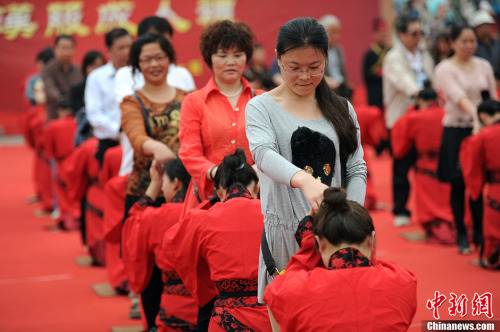 This photo taken on May 1, 2013 shows participants in a Chinese traditional coming-of-age ritual kneel down in front of their parents. Almost 50 young people participated in a Chinese traditional coming-of-age ritual in Xi'an, capital of Shaanxi province, on Wednesday, Labor Day. [CNS/Zhang Yuan]