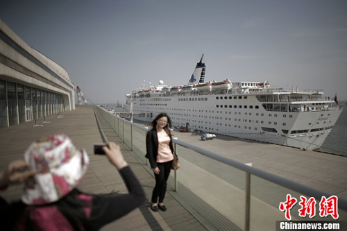 A woman poses before China's first luxury cruise liner, the Henna. The liner started on the Tianjin-South Korea route on Wednesday. [CNS photo]