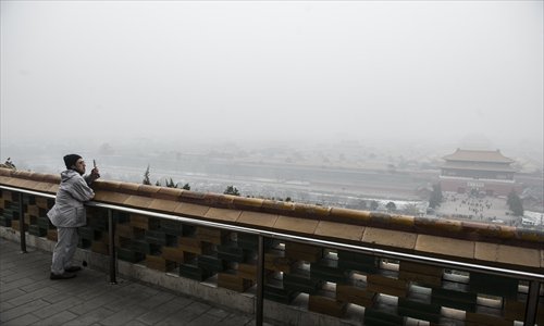 A man takes a photo from a pagoda on top of Jingshan Park looking over the smog-shrouded north gate of the Forbidden City in January. Photo: Li Hao/GT