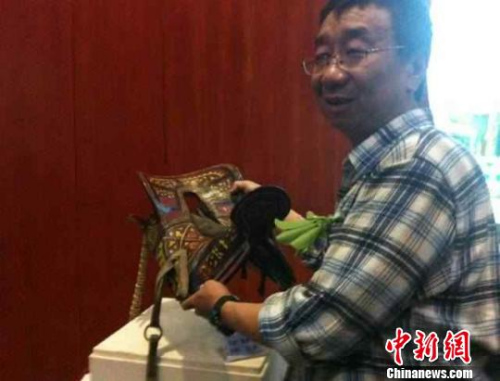 Mu Jihong, the person who named Tea-Horse Ancient Road, poses for a photo with a cultural relic. (CNS/ Wang Lin)