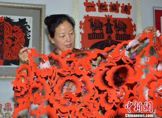 An artist shows a paper-cutting work at an art exhibit held in Taiyuan, Shanxi province.. [Photo: Lv Wei] 