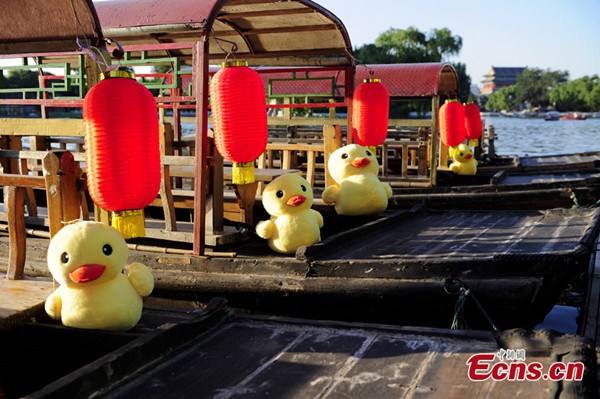 Little rubber ducks are seen on the boats on the Shichahai Lake, Beijing, capital of China, July 16, 2013. The creator of the Rubber Duck, Dutch conceptual artist Florentijin Hofman, has signed an agreement with Beijing Design Week to bring the Big Yellow Duck, as affectionately called by Chinese netizens, to the capital this September. [Photo: CNS] 