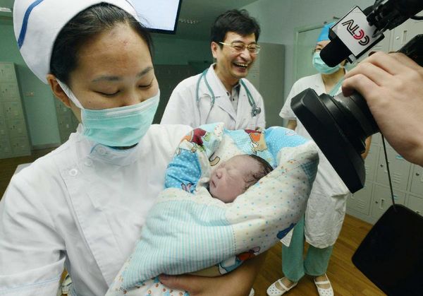 A nurse hugs the baby girl of Qiu, the first pregnant woman in China infected with H7N9 bird flu, in the No.1 People's Hospital of Zhenjiang, east China's Jiangsu Province, July 17, 2013. Diagnosed as H7N9 bird flu patient on April 8, 2013, Qiu gave birth to a girl here on Wednesday.
