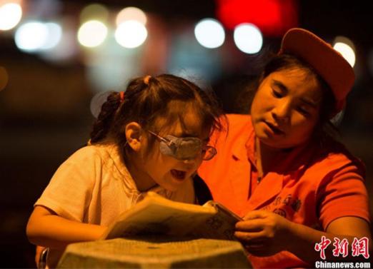 Wu, the sanitation worker, helps her daughter with her homework. [Photo: CNS/Ma Daiguo]
