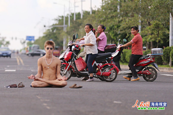   A naked foreign student sits in the middle of a road in Haikou city of South China's Hainan province on September 15, 2013. [Photo/people.com.cn]