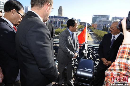 San Francisco Mayor Edwin M. Lee (first on the right) and Chinese Consul General in San Francisco Yuan Nansheng (central) raise the flag from the balcony of City Hall together on September 25, 2013. [Photo: China News Service/ Chen Gang]