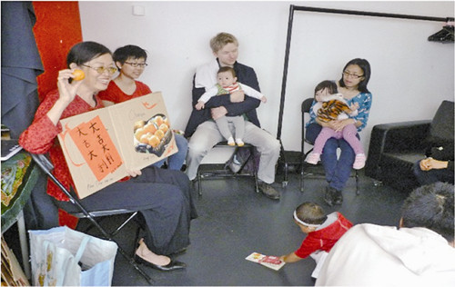 One classroom saw the teacher singing a Chinese song while infants are crawling around, with parents sitting in a circle participating.