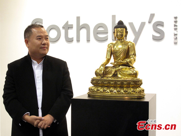 Chinese collector Zheng Huaxing bids 236.44 million HK dollars (30 million US dollars) for a gilt-bronze figure of a seated Shakyamuni Buddha from China's Ming Yongle period and eventually wins it at Sotheby's Hong Kong on Tuesday, October 8, 2013. (Photo: China News Service/Jia Siyu)