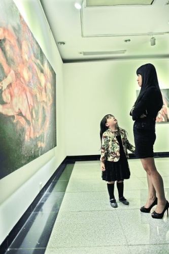 A girl asks her mother what the paintings are about at the exhibition in central China's Hubei province on Oct. 27, 2013.