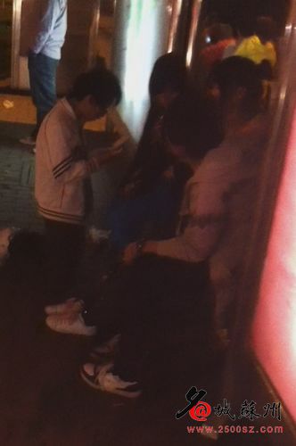 A boy kneeling down in front of a girl wearing a ponytail about the same age, at a bus stop in Wuzhong district.