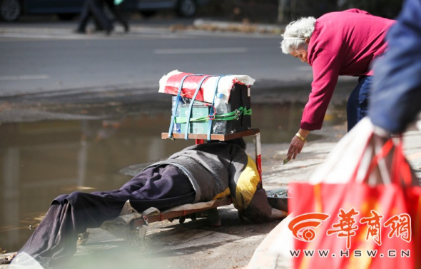 A 77-year-old woman puts one yuan ($0.16) into the money box of the bogus beggar.