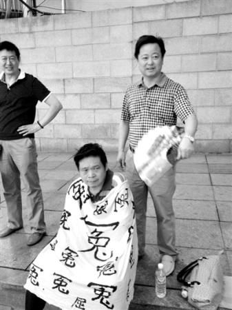 In a photo taken in August, Duan sits on the curb with the same white cloth covering his body. Two smiling officials stand behind him. One has been identified as Pang Yewen, head of the Linli Bureau of Letters and Calls.