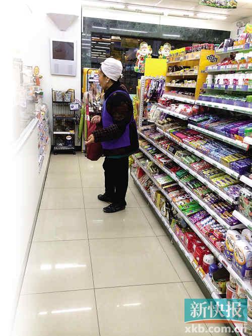 A dama beggar waits around the checkout counter at a supermarket.