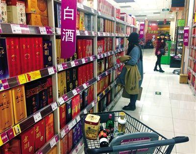 A consumer is picking fancy liquor in a supermarket. Sales of high-grade liquor may decrease in the coming Spring Festival as regulations ban official accepting gifts. (Photo source: the Beijng News)