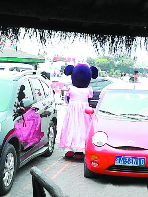 Wang Shizhong in Minnie Mouse costume stands by the street. (Photo source: Chongqing Morning Post)