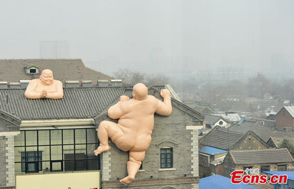 Sculptures of two naked Buddhas are seen on the top of a building in Jinan, capital city of east China's Shandong province on Sunday, Jan. 19, 2014. [Photo/China News Service]