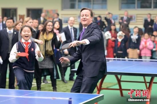David Cameron plays table tennis with students during his visit to a primary school in Chengdu. (Photo: China News Service)