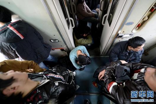 Numbers of passengers holding seatless tickets stand or sit on the floor of train carriage asile. (Photo source: Xinhuanet)