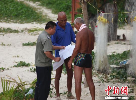 A police officer is handing out printed notices on prohibiting skinny dipping at Sanyas beaches to tourists. (Photo source: Chinanews.com)