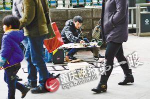 Zhang Qihui is painting on the street with only one thumb. (Photo source: Chongqing Evening News)