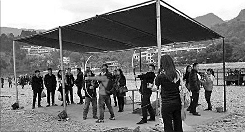 Two tourists are shooting the arrows with several others watching around.