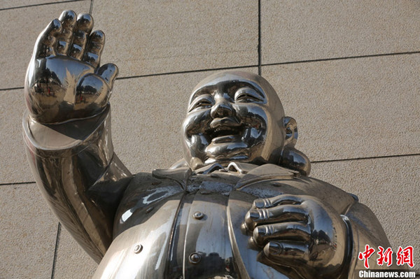 A Laughing Buddha statue wearing a modern trench coat appears in front of a shopping mall in Shenyang, Liaoning province. (Photo source: Chinanews.com)